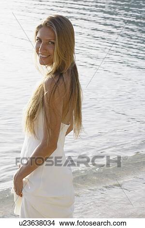 Mid adult woman wearing wedding dress on beach (portrait) View Large Photo Image Picture - Mid adult woman wearing wedding dress on beach (portrait). Fotosearch