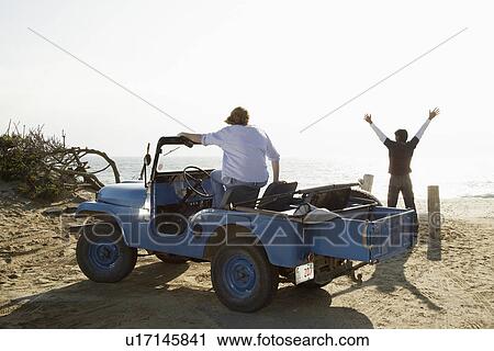 Stock Image - Two men with beach buggy on beach. Fotosearch