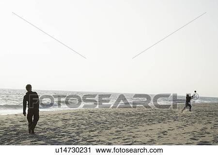 Two people throwing ball on beach View Large Photo Image Stock Image - Two people throwing ball on beach. Fotosearch