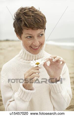 Stock Image - Woman pulling petals off daisy. Fotosearch