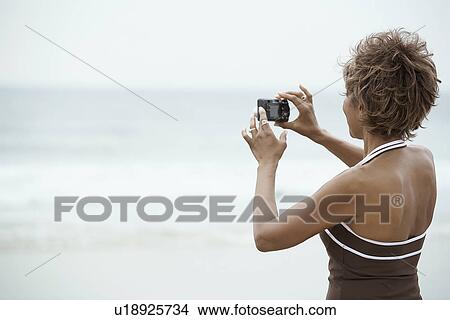 Woman taking digital photograph at beach (rear view) View Large Photo Image Picture - Woman taking digital photograph at beach (rear view). Fotosearch