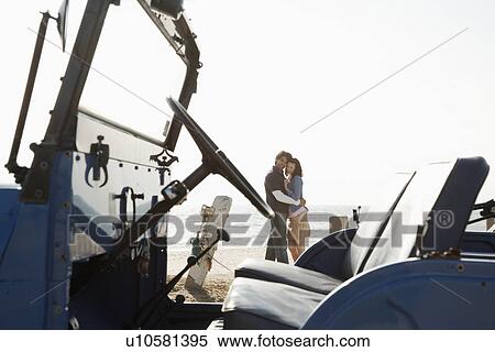 Stock Photography - Young couple hugging near beach buggy. Fotosearch