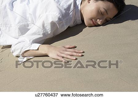 Young woman lying on sand View Large Photo Image Stock Photo - Young woman lying on sand. Fotosearch