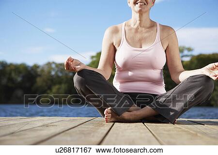 Stock Photo - Mature woman meditating in lotus position (low angle view, low section). Fotosearch