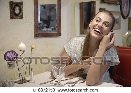 Woman laughing at dining table (portrait) View Large Photo Image Stock Image - Woman laughing at dining table (portrait). Fotosearch