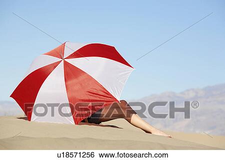 Woman sitting under umbrella in desert View Large Photo Image Stock Photograph - Woman sitting under umbrella in desert. Fotosearch