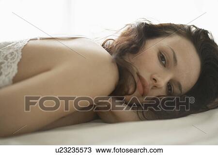 Young woman lying on bed View Large Photo Image Stock Image - Young woman lying on bed. Fotosearch