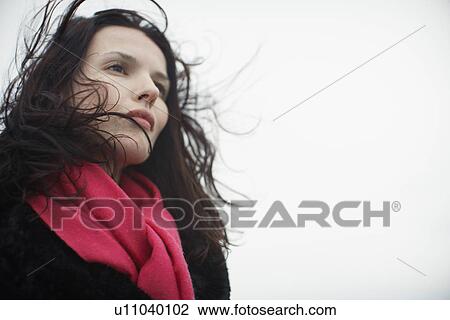 Stock Image - Young woman with tousled hair (low angle view). Fotosearch