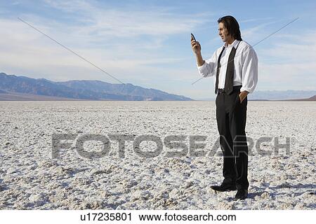 Businessman using cell phone in desert View Large Photo Image Stock Image - Businessman using cell phone in desert. Fotosearch