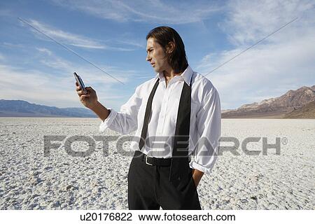 Businessman using cell phone in desert View Large Photo Image Stock Image - Businessman using cell phone in desert. Fotosearch