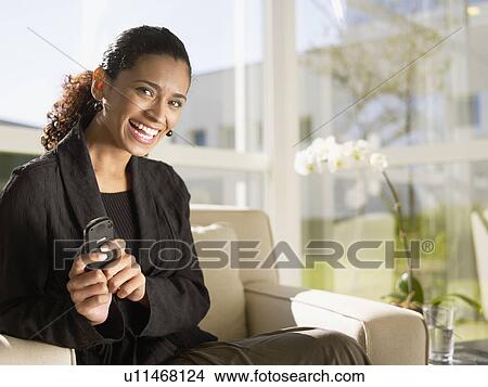 Businesswoman sitting on chair and holding cell phone View Large Photo Image Picture - Businesswoman sitting on chair and holding cell phone. Fotosearch