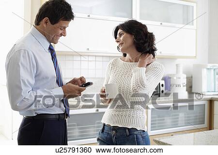 Husband and wife talking in kitchen, husband using cell phone View Large Photo Image Stock Image - Husband and wife talking in kitchen, husband using cell phone. Fotosearch