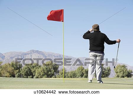 Stock Image - Man on cell phone at golf course. Fotosearch