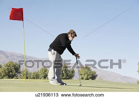 Stock Image - Man on cell phone at golf course. Fotosearch