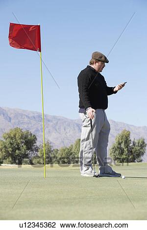 Stock Image - Man using cell phone at golf course. Fotosearch