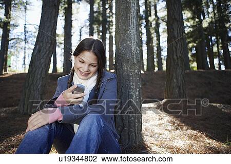 Teenage girl using cell phone in woods View Large Photo Image Stock Image - Teenage girl using cell phone in woods. Fotosearch