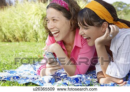 Two young women with cell phone laughing View Large Photo Image Stock Photo - Two young women with cell phone laughing. Fotosearch