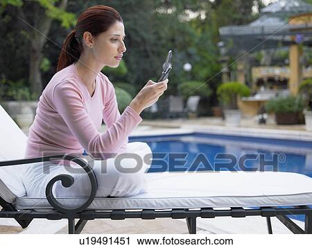 Woman using cell phone by swimming pool View Large Photo Image Stock Image - Woman using cell phone by swimming pool. Fotosearch