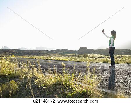 Woman using cell phone on highway, Moab, Utah, USA View Large Photo Image Stock Image - Woman using cell phone on highway, Moab, Utah, USA. Fotosearch