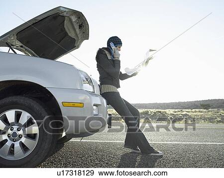 Stock Photo - Woman with road map talking on cell phone by broken car. Fotosearch