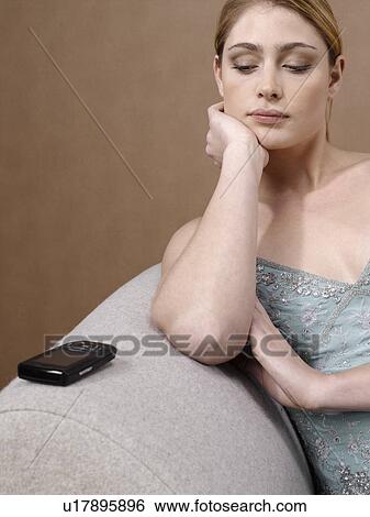 Stock Photograph - Young woman looking at cell phone on armrest. Fotosearch