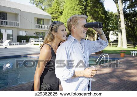 Couple using binoculars by pool View Large Photo Image Stock Photography - Couple using binoculars by pool. Fotosearch