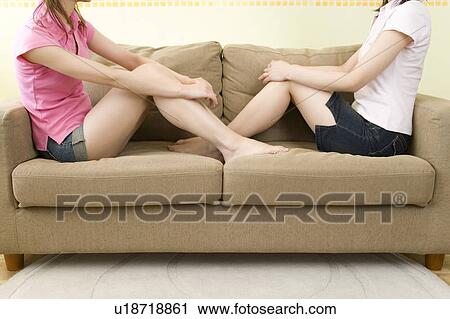 Stock Image - Two Women Sitting on Sofa, Side View. Fotosearch