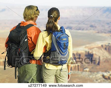 Stock Photo - Young couple looking at rock strata, rear view. Fotosearch