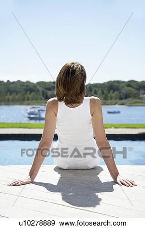 Stock Photo - Woman sitting by pool. Fotosearch