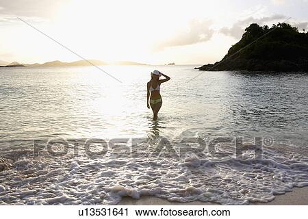 Young woman in bikini walking in ocean, St. John, US Virgin Islands, USA View Large Photo Image Stock Image - Young woman in bikini walking in ocean, St. John, US Virgin Islands, USA. Fotosearch