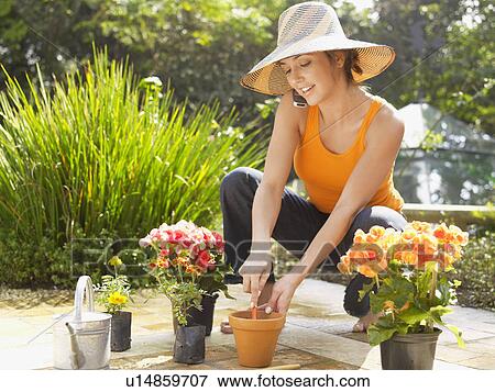 Stock Photo - Young woman planting flowers and talking on cell phone. Fotosearch