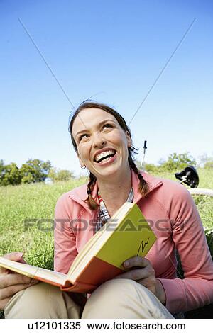 Stock Photography - Young woman reading book in park. Fotosearch