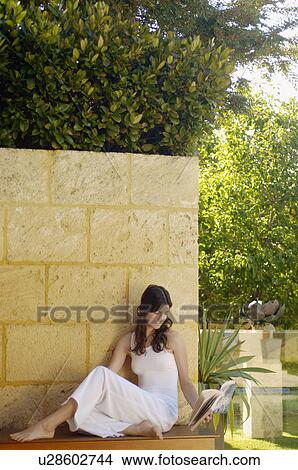 Young woman reading book outdoors View Large Photo Image Picture - Young woman reading book outdoors. Fotosearch