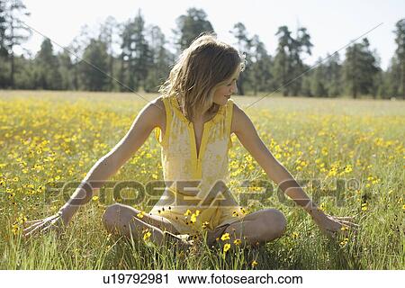 Young woman sitting in a field of wildflowers View Large Photo Image Stock Image - Young woman sitting in a field of wildflowers. Fotosearch