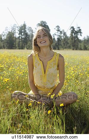 Stock Photo - Young woman sitting in a field of wildflowers. Fotosearch