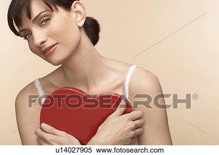 Stock Photography - Mid adult woman holding heart shaped chocolate box. Fotosearch