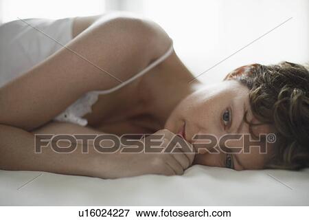 Mid adult woman lying on bed View Large Photo Image Stock Photo - Mid adult woman lying on bed. Fotosearch