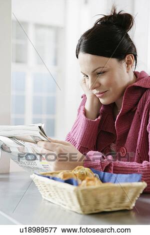 Mid adult woman reading magazine at kitchen counter View Large Photo Image Stock Photo - Mid adult woman reading magazine at kitchen counter. Fotosearch