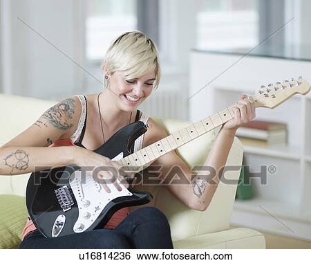 Stock Photograph - Young Woman Playing Electric Guitar. Fotosearch