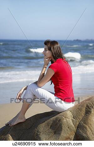 Young woman sitting on rock and looking at ocean View Large Photo Image Stock Photography - Young woman sitting on rock and looking at ocean. Fotosearch