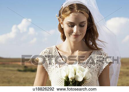 Stock Image - Bride looking at flowers. Fotosearch