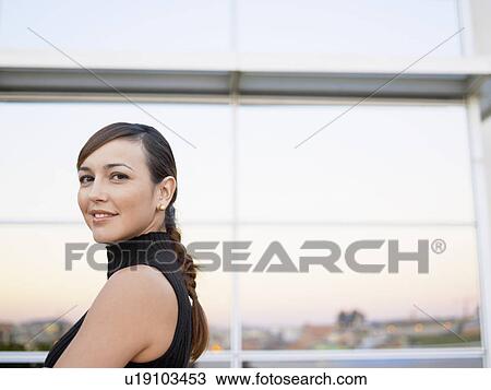 Stock Image - Young woman against windows (portrait). Fotosearch