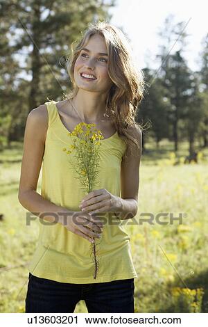 Young woman holding a wildflower View Large Photo Image Stock Image - Young woman holding a wildflower. Fotosearch