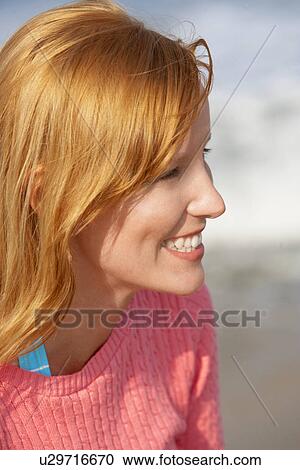 Stock Image - Young woman with ginger hair smiling (profile). Fotosearch