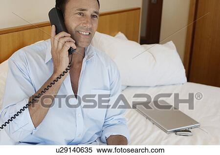 Stock Photography - Businessman on phone in hotel room. Fotosearch