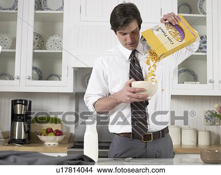 Picture - Businessman pouring cereals in bowl. Fotosearch