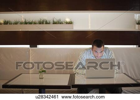 Man using laptop computer on café table View Large Photo Image Stock Image - Man using laptop computer on café table. Fotosearch