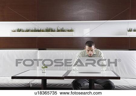Stock Photography - Man using laptop computer on café table. Fotosearch