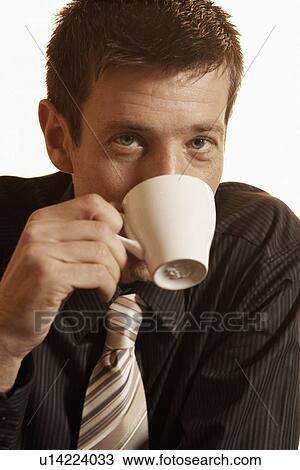Stock Image - Mid adult businessman drinking coffee. Fotosearch