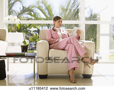 Businesswoman reading newspaper on chair View Large Photo Image Stock Image - Businesswoman reading newspaper on chair. Fotosearch